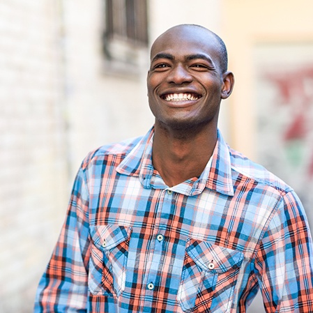 Smiling man in patterned shirt walking down the street