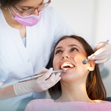 Dentist examining dental patient's smile after placing dental crown