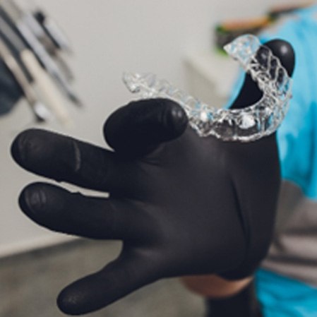 Dentist with black gloves holding Invisalign aligner