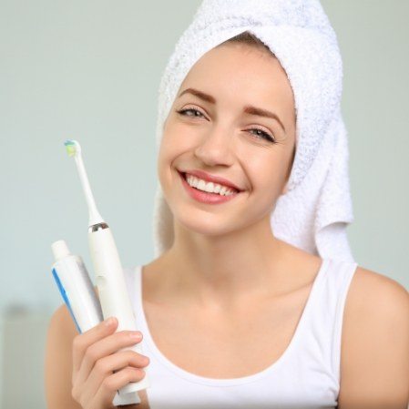 Smiling woman holding a toothbrush and toothpaste