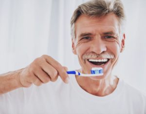 senior man smiling while brushing teeth